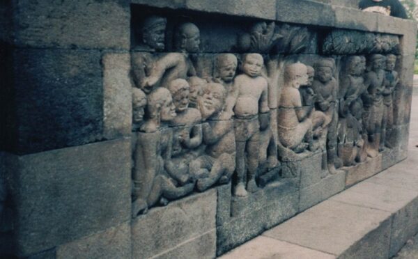 Lost and forgotten, the temple lay in the heart of a thick forest embraced by a mantle of green, its ancient walls smothered by vines, ferns and shrubs of every description. By day and at night, the only sounds were those of the leopard, or the shrieking of monkeys, the piercing trill of birds, and other denizens of the jungle. For over a thousand years, Borobudur the largest Buddhist monument in the world, was a word that was only a spectral memory, confined to the realms of invisibility. The eternal reverie of this architectural marvel came back to life in 1815 when it was rediscovered by a Dutch Engineer working under Sir Thomas Raffles the Governor of Java. This chance discovery which was one of the greatest archaeological discoveries at the time revealed the magnitude of the builders and architect's skills to a stunned world. It sent ripples of excitement through historical and archaeological seats of learning, and to this day continues to enthrall visitors leaving them bewildered with wonder. Borobudur is not just a Buddhist temple in the ordinary sense of the word. It is a colossal Buddhist Monument in which the teachings of the Buddha have been bought to life by the excellent sculpture and the relief panels to be seen. As you begin your visit at ground level, you embark on a journey through which, by the time you reach the third tier of this colossus, you have practically "read" the teachings of Lord Buddha depicted in all the sculpted relief panels with a level of skill beyond this world. On a beautiful Javanese morning slightly shrouded in mist when the golden rays of sunshine were beginning to greet the dawn of the day, I took my first steps towards this miracle in stone as I perceived it looming large and inviting beyond belief, hardly believing my eyes. I was looking at a sight from an ethereal world. I was on a six week tour of Indonesia and this to me was an odyssey of the soul because Borobudur was the highlight of my visit to this beautiful and beguiling country. Today Borobudur is as enigmatic, mysterious, and beyond beautiful as it was over 1200 years ago. When first "discovered" in 1815 it was a tangle of statues displaced from their pedestals by enormous roots, some locked in the embrace of giant branches while others lay hurled to the ground. When fully excavated, Borobudur caused the world to hold its collective breath as the complex intricacies in her statues, carvings and construction were revealed. The Architect or Architects, the Builders, the Surveyors the Stone Masons, Stone Cutters, and the Intelligentsia harnessed to embark on this massive project had to be beyond brilliant ! The Blueprint of the complex was that it had to be built in the form of a Buddhist symbol known as a "Mandala" which is a representation of the cosmos. An aerial view today shows the entire temple resembling a colossal "Mandala" - in other words, a vision of the cosmos in stone. At the base, it begins in the daily world one lives in and then spirals up to Nirvana. A series of reliefs at the base represent a world of sin, and only the good are rewarded by a higher standard of life in reincarnation. Along the Pilgrim's Walk which is about 3.2 miles, the Master Sculptor has excelled by carving some richly decorated narrative panels which is a doctrine of Buddhist teaching. There are panels of Queen Maya, and the birth of Prince Siddhartha Gautama, and his journey to enlightenment. The third platform of the monument by its circular shape, symbolizes Nirvana which never ends. The outcome of this stroke of genius was that a pilgrim could walk from the base of the temple to the very top through two miles of corridors and stairs by "reading" the panels on his/her last journey. If a devout pilgrim "fine tuned" his/her antenna to the religious sensitivities and the message on the panels, he or she would literally "see"and "hear" the messages in the Dhammapada on her journey to Nirvana. Although mystery surrounds the origins of Borobudur since there are no records of its construction, radio carbon dating confirms that it is over 1200 years old. The consensus among Historians and Archaeologists is that work on Borobudur commenced in the mid to late 8th century by rulers of the Sailendra dynasty. JOY AND DESPAIR. Built between 778 and 824 CE during the reign of King Samaratungga of the Sailendra dynasty, the mammoth task of conforming to the Architects plans would have daunted lesser men. But a massive labour force was recruited and it is estimated that 70,000 cubic metres of stone was hewn, transported and carved during construction. I first heard of Borobudur from a book which I borrowed from my library 35 years ago. When I read the name "Samaratungga" my heart leapt for joy ! This is a Sinhalese name and the thought that a King of Lankan ancestry possibly had some connection with royalty in this part of Indonesia filled me with eagar anticipation ! When I broached the subject with my Guide who incidentally was well versed with the local history of the area, he very politely gave me chapter and verse of their ancient history which proved that although "Samaratungga" sounded like a Sinhalese name, it was one hundred percent indigenous. That burst my bubble and I hid my disappointment bravely with a lot of diplomacy ! He then proceeded to give me some building statistics which he stated was the opinion of some of the learned Building Engineers of the day. Borobudur he told me was built from two million stone blocks in the form of a stupa symmetrical in shape around a small hill. The monument stands on a base measuring 118m by 118m. It has six square terraces with four circular ones at the top, which is reached by four gateways. Linguists inform us that the word "Borobudur" is derived from Sanskrit and means "Vihara Buddha Uhr" which in turns means "The Buddhist Monastery on the Hill". We know now that it is more than just a 'Monastery' - it is a pristine Buddhist work of art unequalled anywhere in the world. Nature too has lent a hand because Borobudur is located in stunningly beautiful landscape and locals call it "The Garden of Java". Historians infer that in the 10th and 11th century this magnificient jewel in the crown was abandoned due to the shift of political power to East Java, following the decline of Buddhism. Like the mystery surrounding its construction, Archaeologists are at a loss to understand why it was abandoned (possibly due to volcanic activity in the area ?) and thus followed Borobudur's long dark night of the soul where it lay buried in the jungle until its chance discovery in 1815. My Guide informed me that in 1975 the Indonesian Government began a massive cleaning and restoration effort in partnership with UNESCO, and this resulted in the Monument gaining worldwide attention. It was granted UNESCO World Heritage Status in 1991 and is today the most popular tourist site in Indonesia. I found Indonesia to be a land of Mother Nature's masterpieces, its geography offering extraordinary natural diversity, and excelling in outstanding natural beauty. Mountainous and wild, richly forested and deeply rural, picture book scenic views come at you from all angles - and looming in the distance are the volcanoes which ominous as they look, somehow add to the scenic beauty. It is a cultural conundrum as thrilling as it is overwhelming. The country held an inexhaustible fascination for me in its culture art and history. In the villages, traditional lifestyles are maintained even in the face of rampant modernisation. The adventure is endless. What you make of it is up to you. Bernard VanCuylenburg.